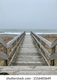 Weathered Wooden Boardwalk Beach Path Leading Directly Into The Sea On A Cloudy Day, Symmetrical Vanishing Point In The Middle Distance, Symbolizing A Journey