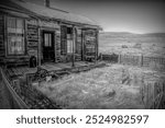 A weathered wooden house with porch in Bodie ghost town, California. The abandoned frontier homestead showcases preserved Wild West architecture against a barren desert landscape.