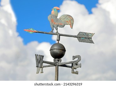weathervane in metal with form of a cockerel with cardinal points