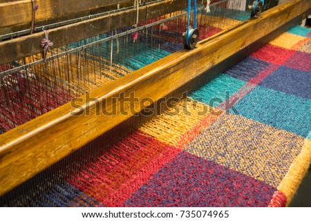 A weaving loom producing brightly colored woolen fabric in an Irish woolen mill.