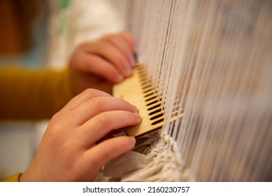 Weaving on a large wooden loom. Closeup of hands.