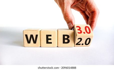 WEB 2 or 3 symbol. Businessman turns a wooden cube and changes words WEB 2.0 to WEB 3.0. Beautiful white table, white background, copy space. Business, technology and WEB 2.0 or 3.0 concept.