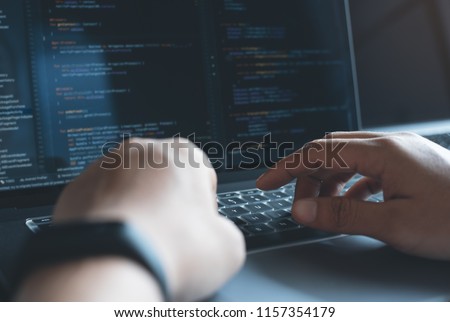 Web or application development, business and technology concept. Programmer, man software developer hands coding HTML, programming Javascript on laptop computer screen, back view close up