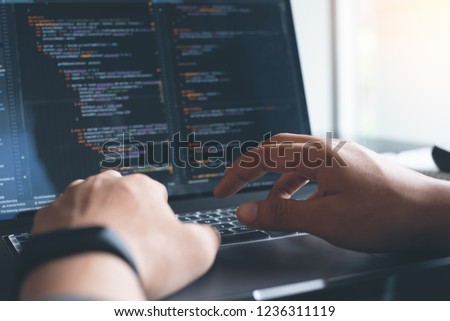 Web or application development, business and technology concept. Programmer, man software developer hands coding HTML, programming Javascript on laptop computer screen, back view close up