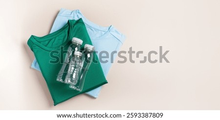 Web banner border with plastic bottles and folded t-shirts, flat lay, concept of clothing production from recycled plastic materials, top view, copy space