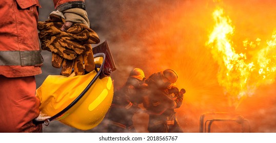 Equipo de bomberos de concepto de banner web, casco de seguridad y guantes resistentes al calor en la mano sosteniendo después de trabajar en segundo plano con un equipo profesional de bomberos trabajando pulverizando agua a alta presión al fuego.
