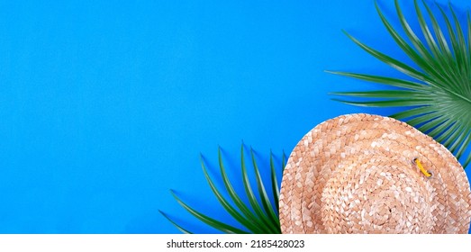 Web Banner With Straw Hat And Palm Leaves On Blue Background. Mockup With Copy Space. Beach Vacation