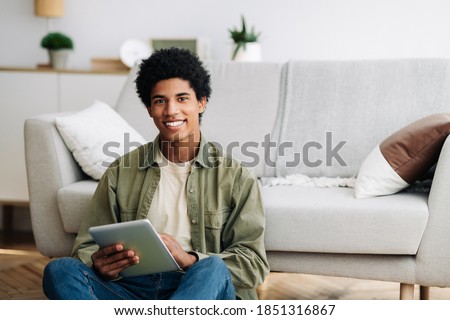 Web based learning. Positive black male student with tablet computer looking at camera and smiling at home, copy space. Happy teenager taking online degree program, attending web class