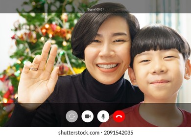 Web Cam Video Call Shot Of A Lovely Asian Mother And Son Cheerful Smile And Say Hello To Their Distance Family On Christmas Eve During Covid 19 Pandemic. 2022, New Normal, Technology, Application.