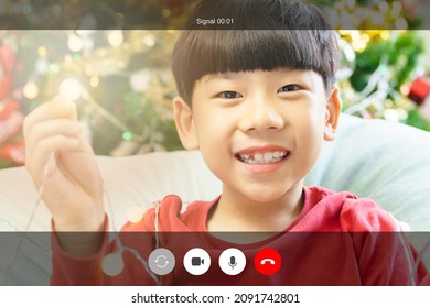 Web Cam Video Call Shot Mock Up. An Adorable Asian Little Boy In Red Sit In Front Of A Bright And Full Decoration Christmas Tree Cheerful Smiling To Family Through Online Chat Application On Christmas