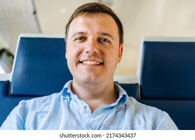 Web Cam View Of Confident Millennial Man Looking At Camera With Joyful Expression On Face While Riding In Commuter Train. Happy Middle Aged Guy In Casual Video Call Head Shot Portrait