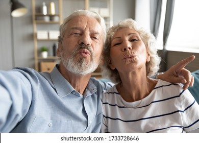 Web Camera View Childish Middle Aged Married Family Couple Having Fun, Taking Kiss Selfie Photo At Home. Playful Older Mature Hoary Man Cuddling Happy Retired Wife, Recording Funny Video Indoors.