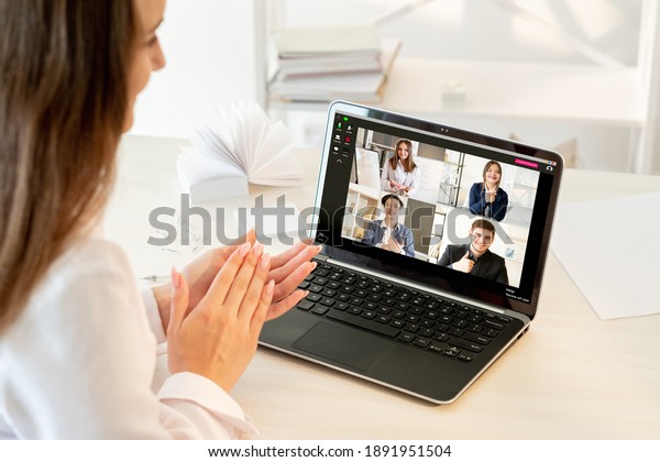 Web conference. Online presentation. Virtual\
meeting. Pandemic WFH. Cheerful diverse multiracial team supporting\
idea applauding to colleague on laptop screen at light modern home\
office workplace.