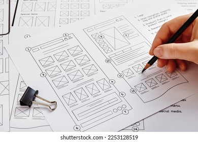 Web design project concept. Close up photo of a UX designer working on website project with a large number of wireframe sketches.