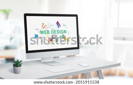 Web design studio with computer display on office desk. Creative web page with web design text surrounded by tools concept