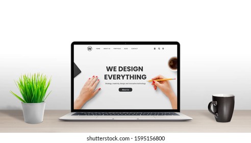 Web design studio concept. Latop with modern, flat design agency web page on desk. Plant and cup of coffee beside