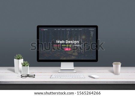Web design studio concept. Work desk with computer display and modern design web agency page.