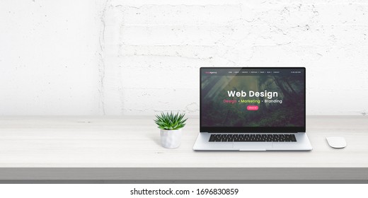 Web design studio promo web site concept on laptop display. Free space beside for promo text on white wall