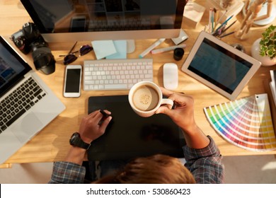 Web designer drinking coffee at workplace, view from above - Powered by Shutterstock