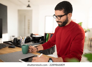Web designer happy handsome bearded hispanic man wearing casual outfit and eyeglasses sitting at desk, working at office, using modern gadgets, digital tablet, pc, drinking coffee - Powered by Shutterstock