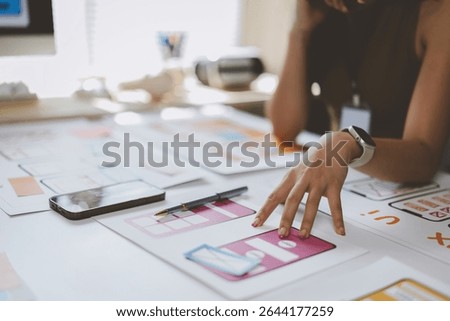 Web designer pointing at mobile application screens and working on user interface and user experience design