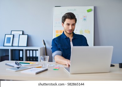 Web Designer Working On Laptop In Office