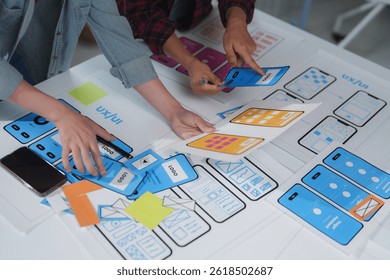 Web designers are building user interface for mobile application, collaborating on wireframes and prototypes, discussing user experience and interface elements