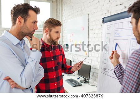 Web designers standing at office planning website layout on flipchart