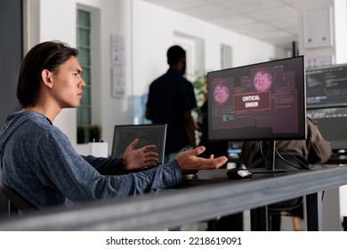 Web developer doing i don t know gesture while having web server hacked, looking at critical error on computer screen in it office. Engineer trying to solve hacking problem, firewall security.