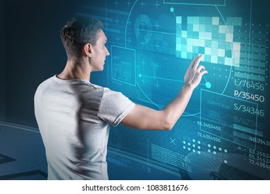 Web developer. Experienced web developer touching the transparent screen and looking interested while working alone