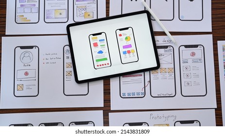 Web developer workplace with sketches of mobile application on wooden table. Flat lay, Top view.