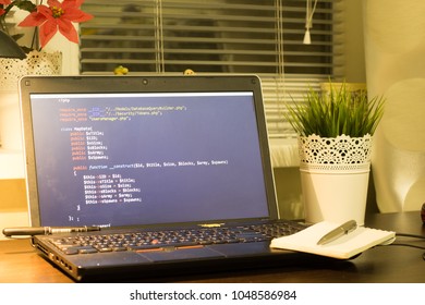 Web developer's workplace. Laptop with a blocknote and a metal pen. Digital technology modern background. Code is created by myself.
