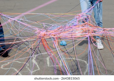 A web of multi-colored knitting threads during a group communication game