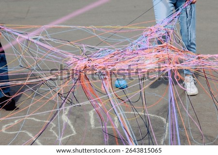 A web of multi-colored knitting threads during a group communication game