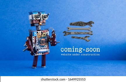 Web site under construction Coming Soon page. Toy robot looks at a set of hand wrenches for maintenance repairs and service works. Blue background