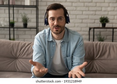 Web teacher. Confident millennial man tutor wearing glasses headset talk to camera give remote lesson. Serious young male in headphones has job interview speak to client consult customer by video call