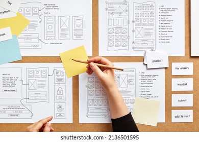 Web UX designer working on mobile responsive website project. Flat lay image of numerous website wireframe sketches and card sorting technique over product designer desk. 