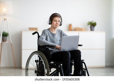 Web-based Education For Disabled Students. Happy Teen Boy In Wheelchair Communicating Online With Tutor On Laptop