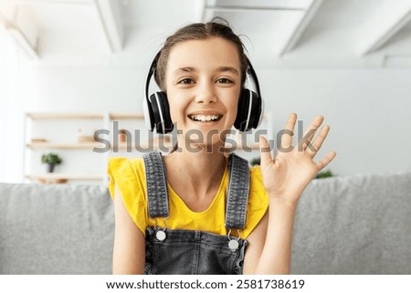 Web-based Education, Remote Communication Concept. Portrait of smiling girl wearing wireless headphones studying at online school, attending distant course using pc waving hand hi, webcam view