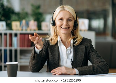 Webcam Portrait Of A Friendly Successful Mature Lady. Confident Business Woman In A Headset Communicates With Colleagues By A Video Conference, Gestures With Her Hands, Looks At The Camera With Smile.