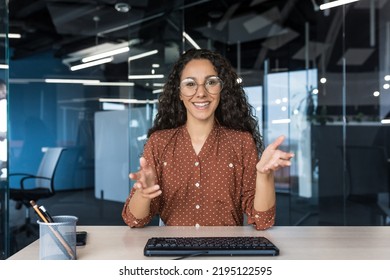 Webcam view, happy hispanic businesswoman smiling and looking at camera, video call with colleagues, remote meeting, female worker in modern office wearing glasses and curly hair