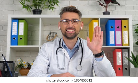 Webcam View Smiling Man Remote Doctor Wears White Medical Coat Sits On Chair At Desk In Hospital Office Greets Patient Online Video Call Chat Laptop Computer, Distance Health Consultation