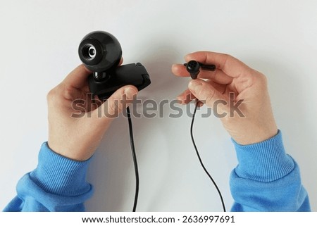 Webcam and wired microphone in hands of Caucasian woman. White background.