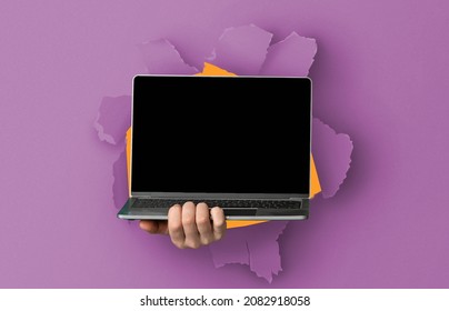 Website Ad Promo, Great Offer. Person holding pc laptop with black empty isolated screen showing device breaking through violet paper sheet. Blank gadget display with free copy space, mock up template