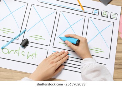 Website designer creating wireframe on paper with highlighter at wooden table, top view