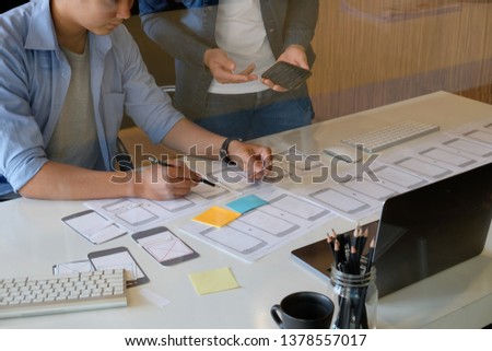 Website designer planning application development draft template layout framework and coding program on paper and computer.