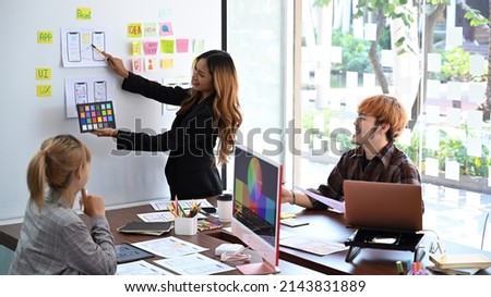 Website developer team brainstorming and planning wireframe layout design application for mobile phone together.