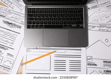 Website development. Sketches of wireframes, laptop and pencil on wooden table, flat lay