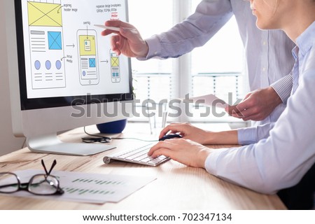 Website development team sketching wireframe layout design for responsive web content, two UI/UX front end designers in office