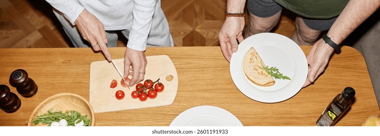 Website header shot of hands cutting tomatoes on cutting board next to plate with folded omelet and arugula while other person holding bowl with greens